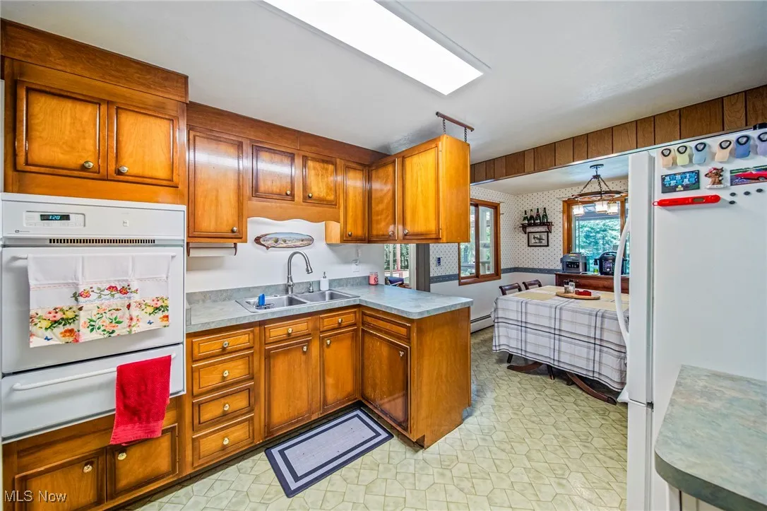 Kitchen featuring white appliances, brown cabinetry, and light flooring