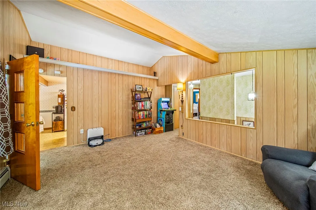 Carpeted living room with wood walls and a textured ceiling