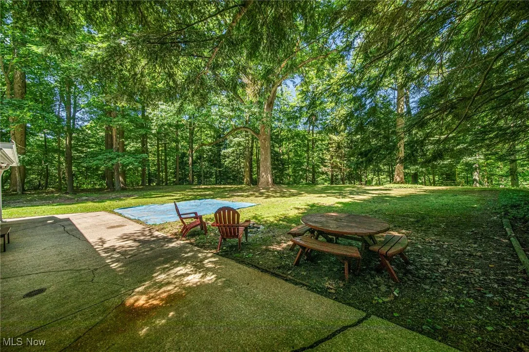 View of green lawn featuring a patio area and a fire pit
