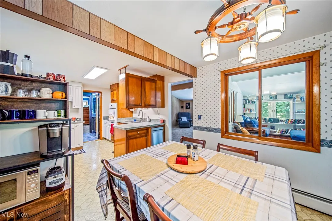 Dining area with wallpapered walls, a baseboard heating unit, healthy amount of natural light, and a chandelier