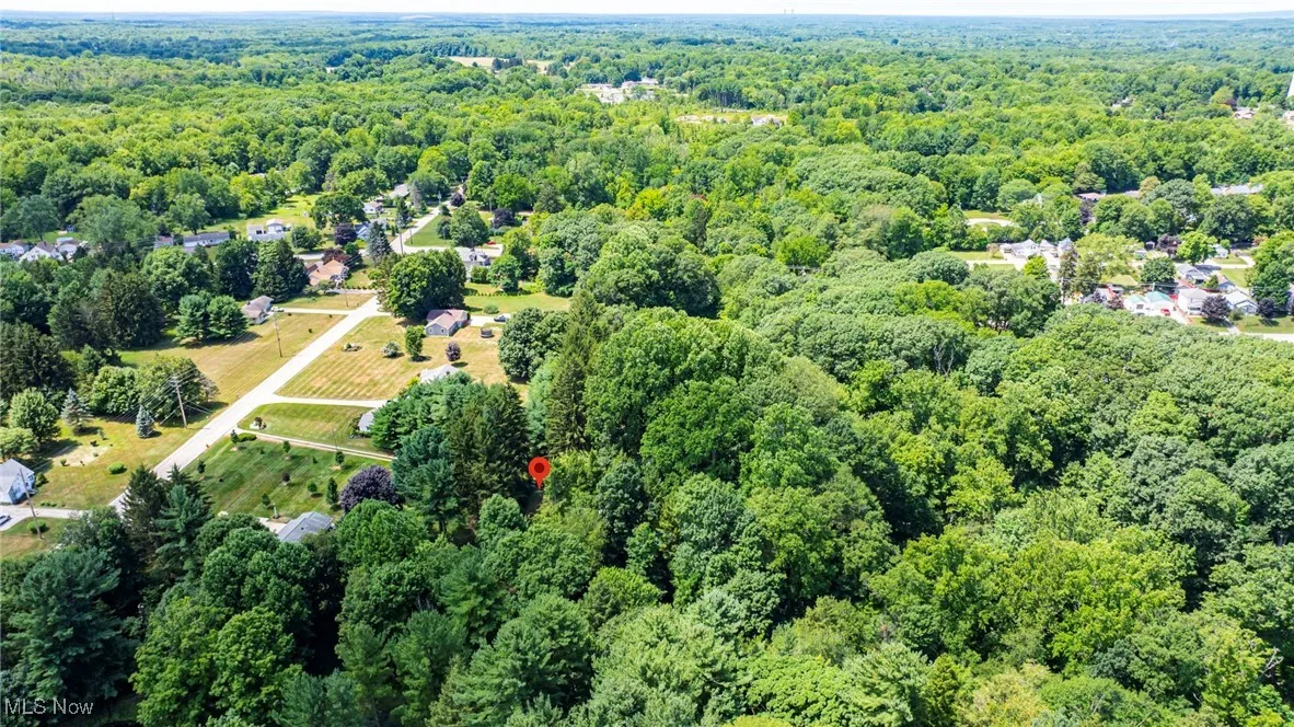Aerial view of property and surrounding area with a forest