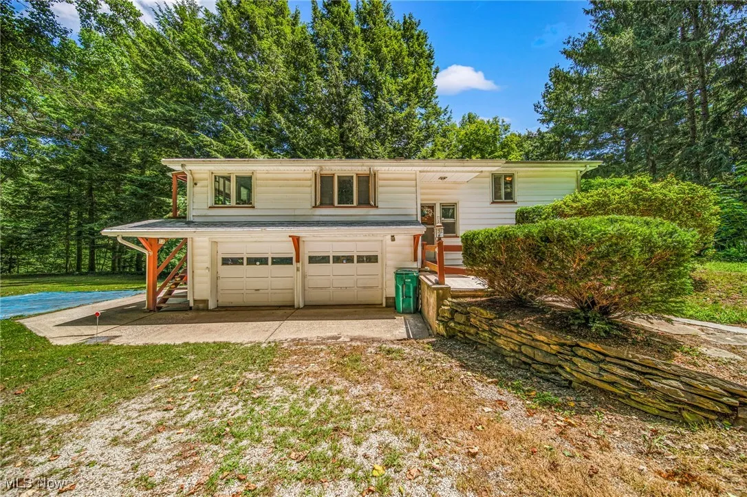 Raised ranch featuring driveway, a garage, and a front lawn