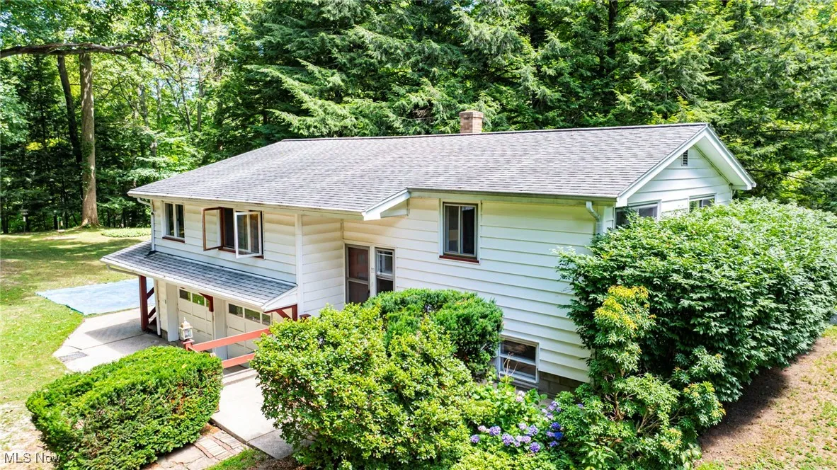 Bi-level home with roof with shingles, a chimney, and a front yard