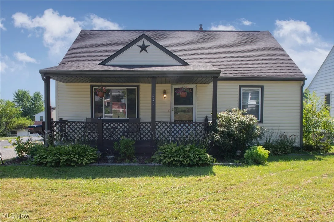 View of front of house with covered porch, a front yard, and roof with shingles