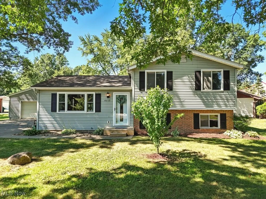 Tri-level home with a garage, brick siding, and a front yard