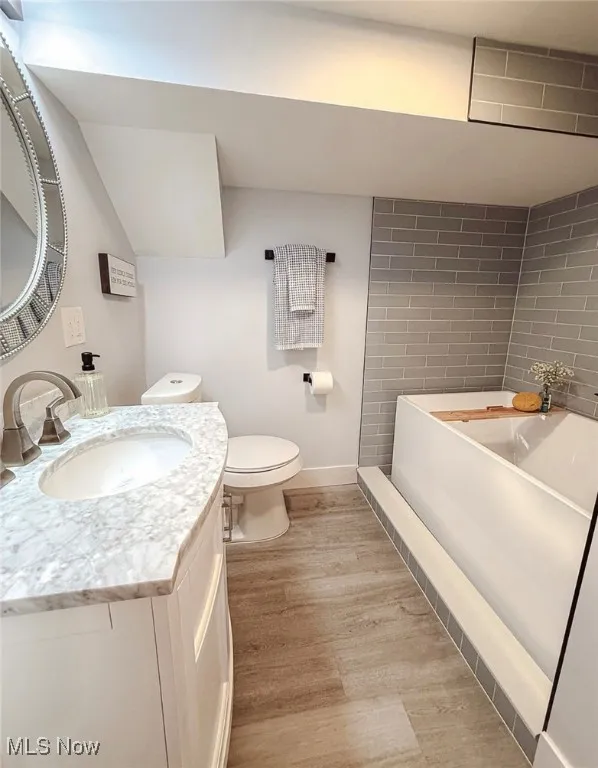 Bathroom featuring a bath, vanity, and wood finished floors