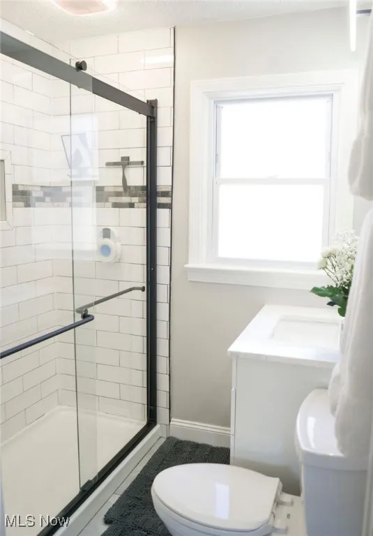 !st floor Full bath featuring a shower stall, a textured ceiling, and vanity
