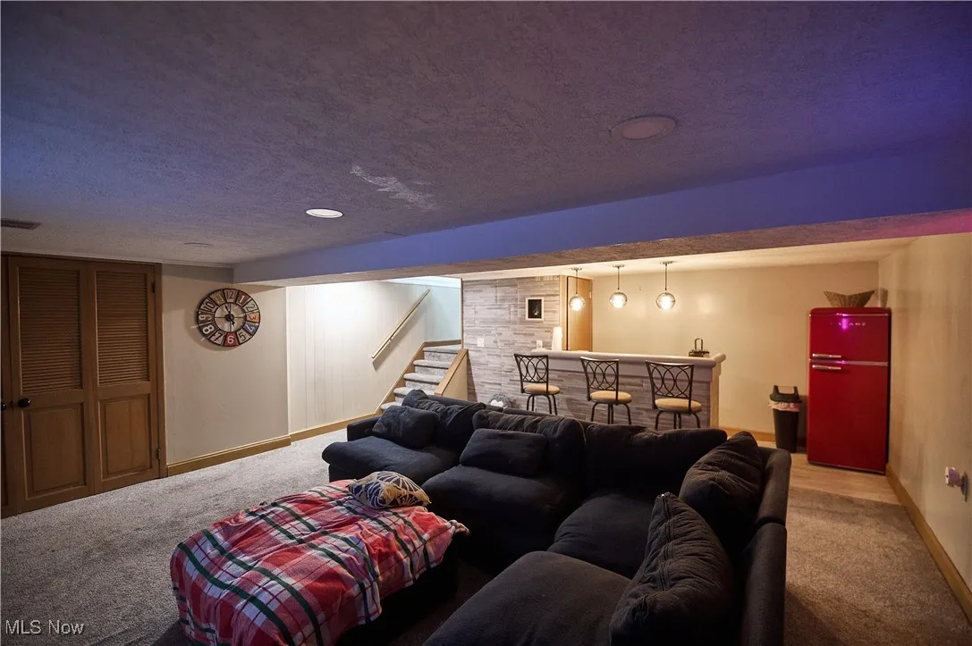 Carpeted home theater featuring bar and a textured ceiling
