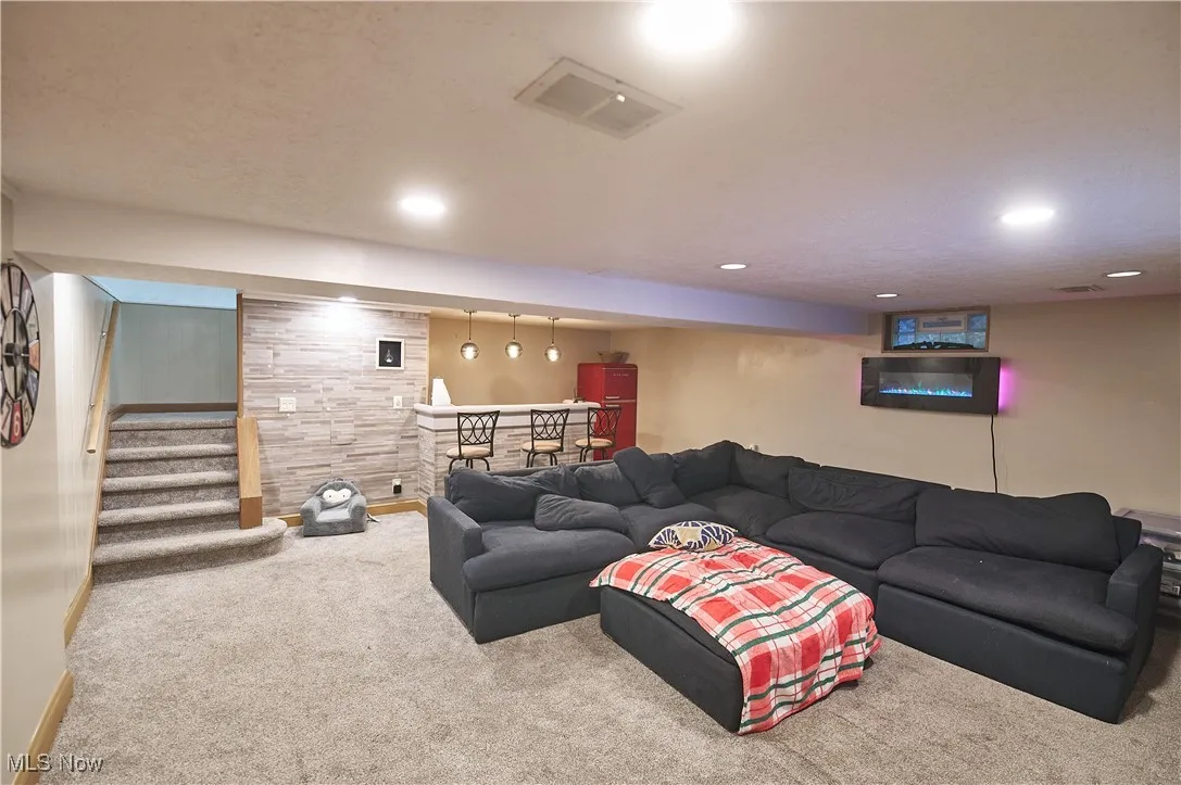 Living area with carpet floors, a bar, recessed lighting, stairs, and a textured ceiling