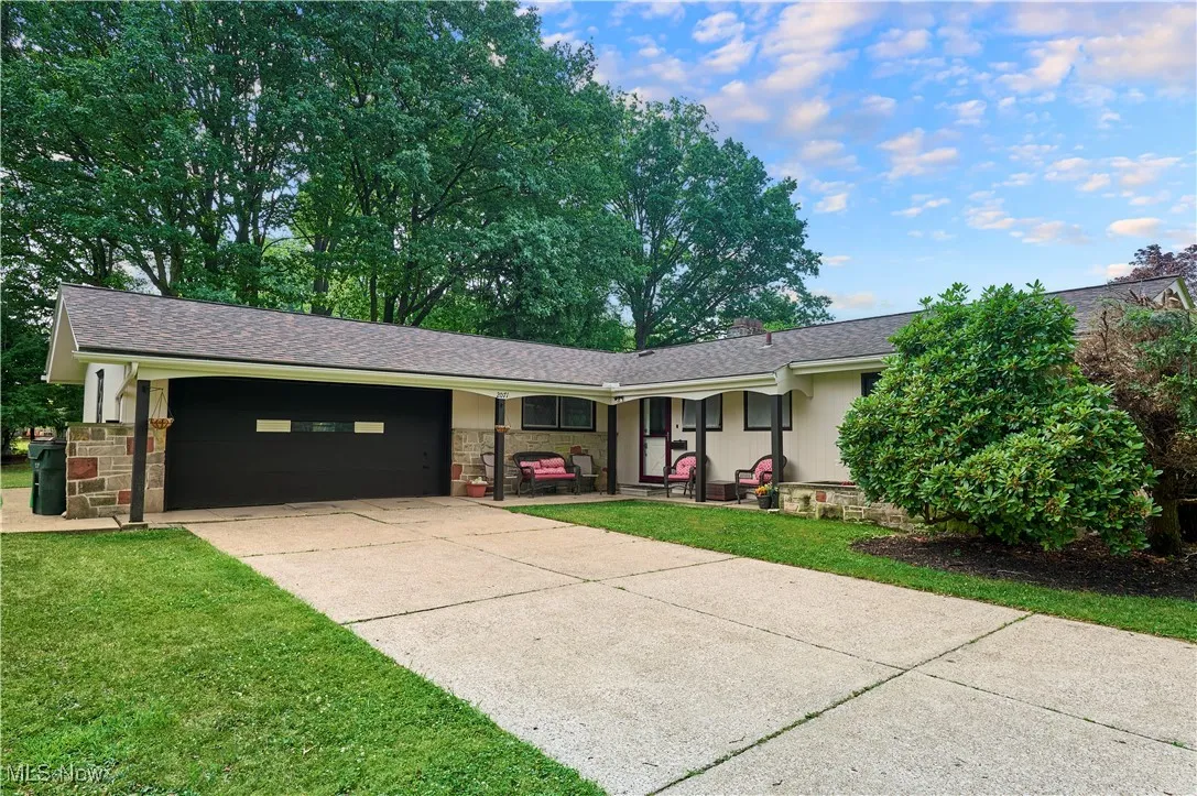 View of front of property featuring concrete driveway, an attached garage, roof with shingles, and a front lawn