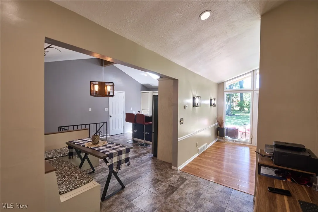 Hall featuring a textured ceiling, lofted ceiling, and a chandelier