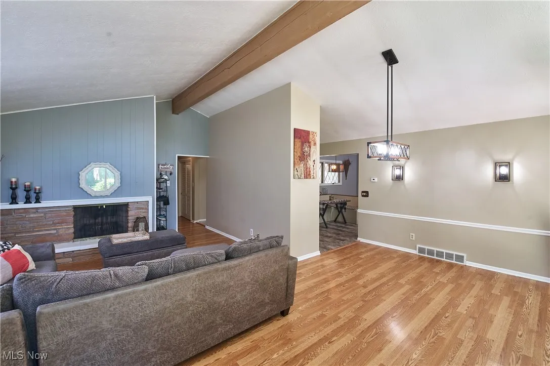 Living area featuring wood finished floors, a stone fireplace, and a textured ceiling