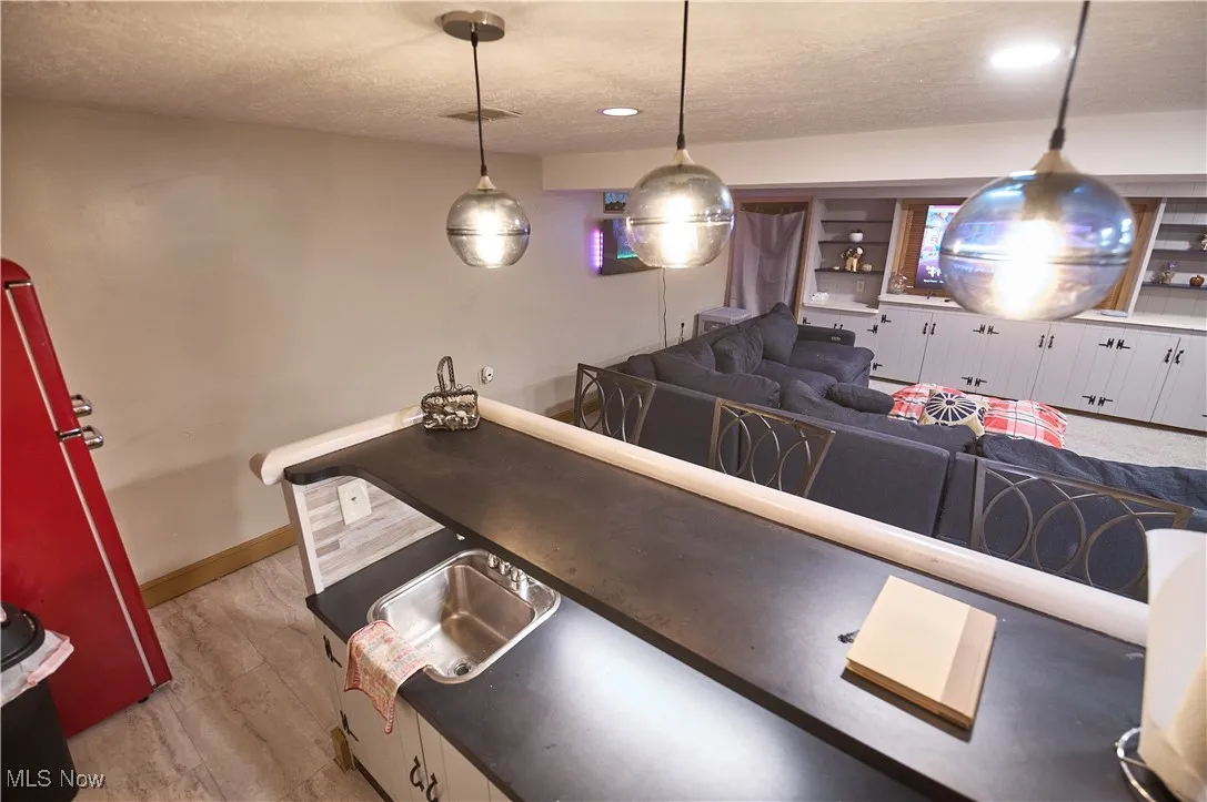 Kitchen with a textured ceiling, light wood-style flooring, pendant lighting, recessed lighting, and white cabinetry
