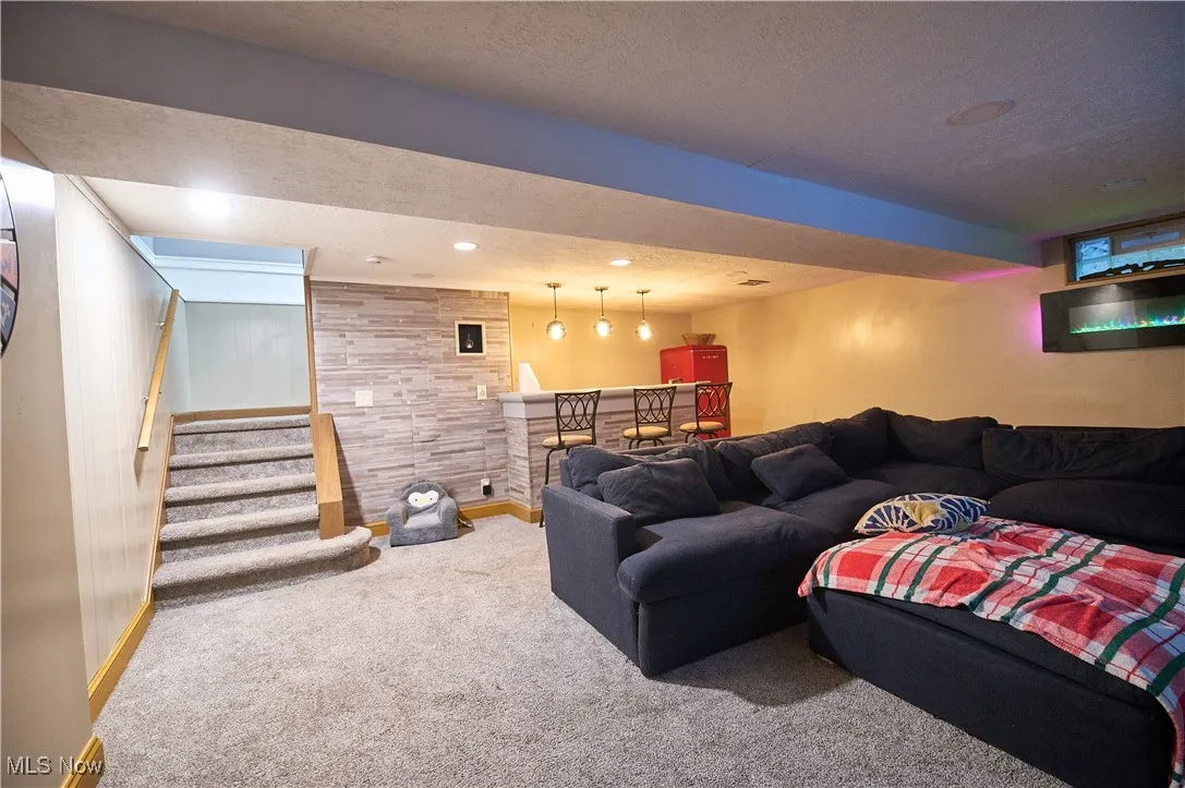Carpeted living room with a dry bar, a textured ceiling, stairs, and recessed lighting