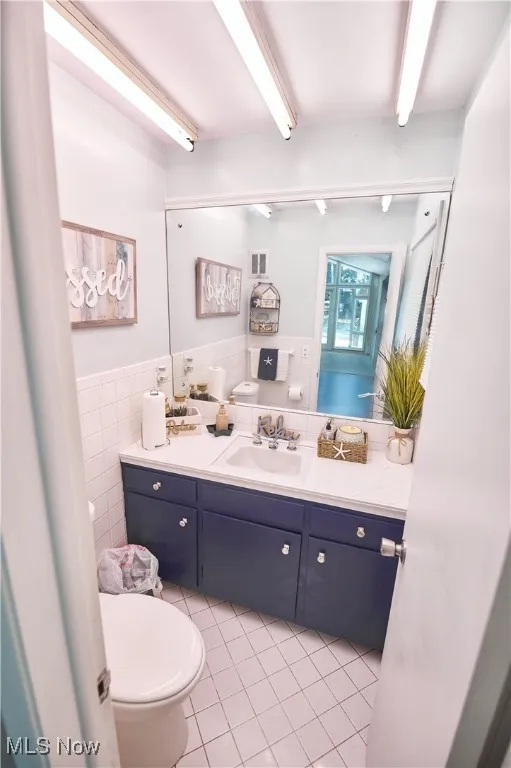 Bathroom featuring tile walls, vanity, tile patterned flooring, and a wainscoted wall