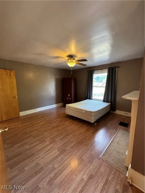 Unfurnished bedroom featuring a textured ceiling, wood finished floors, and a ceiling fan