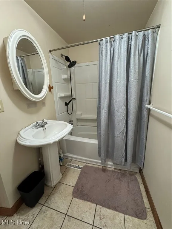 Full bathroom with shower / bath combo with shower curtain and tile patterned flooring