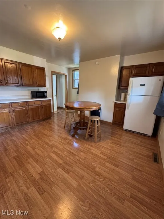 Kitchen featuring fridge, wood finished floors, and light countertops