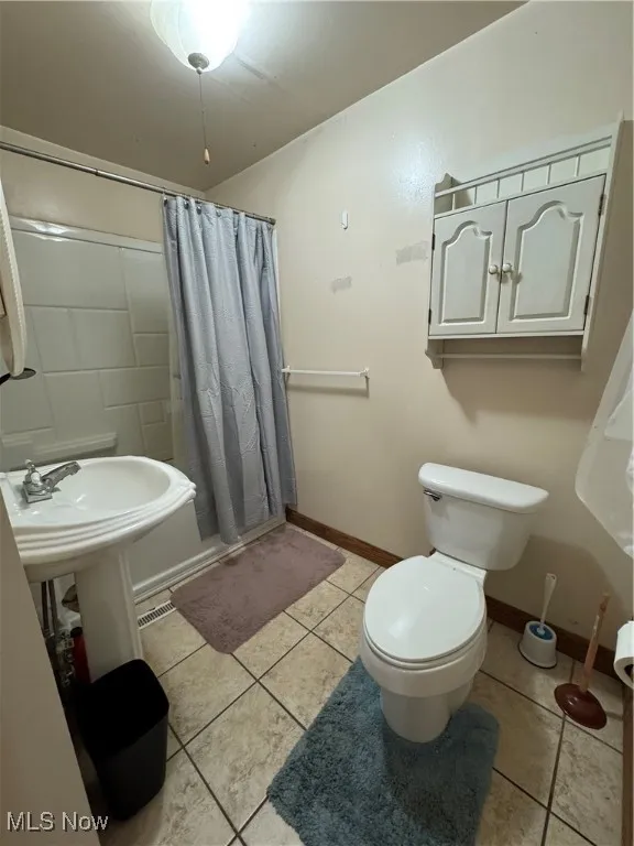 Full bathroom with tile patterned floors and a shower with curtain
