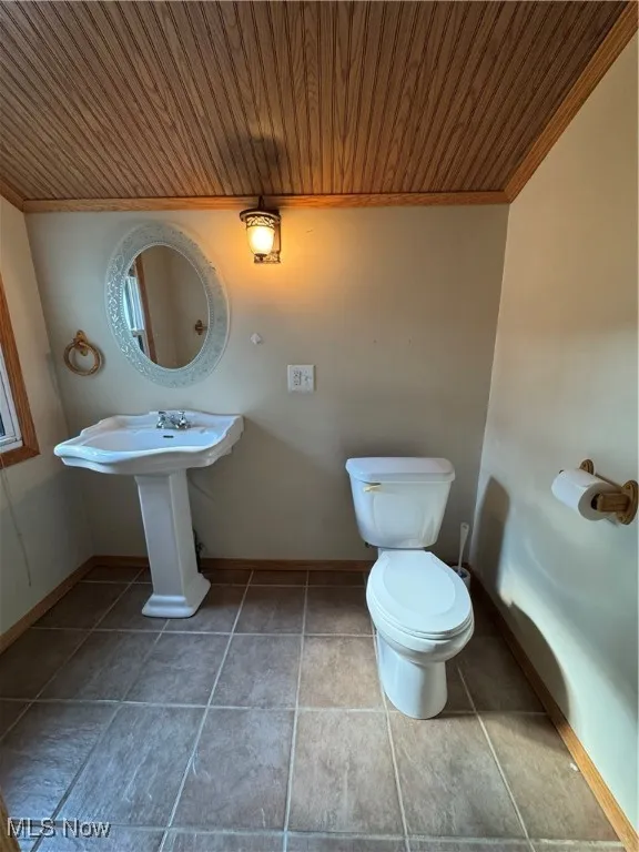Half bathroom with wooden ceiling, tile patterned flooring, and crown molding