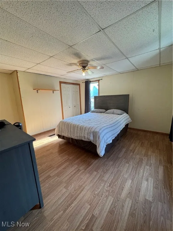 Bedroom featuring a drop ceiling, wood finished floors, and ceiling fan