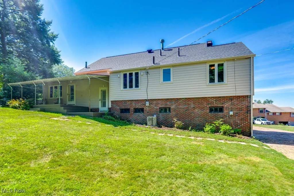 Rear view of house with a lawn and brick siding