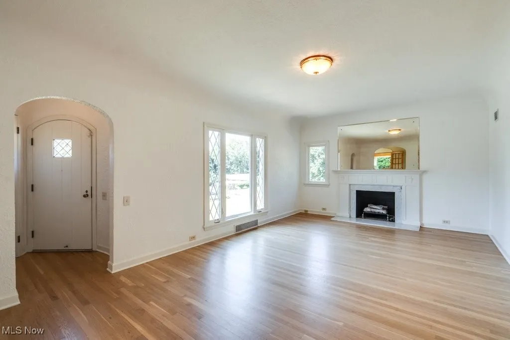 Unfurnished living room featuring light wood-style floors, a premium fireplace, and arched walkways