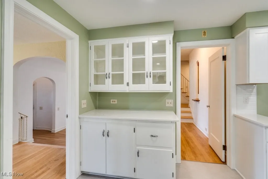 Bar area featuring arched walkways, light wood finished floors, and stairway