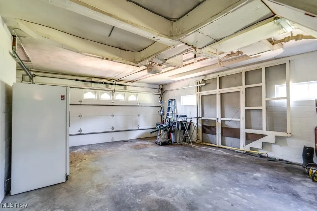 Garage with freestanding refrigerator and a garage door opener