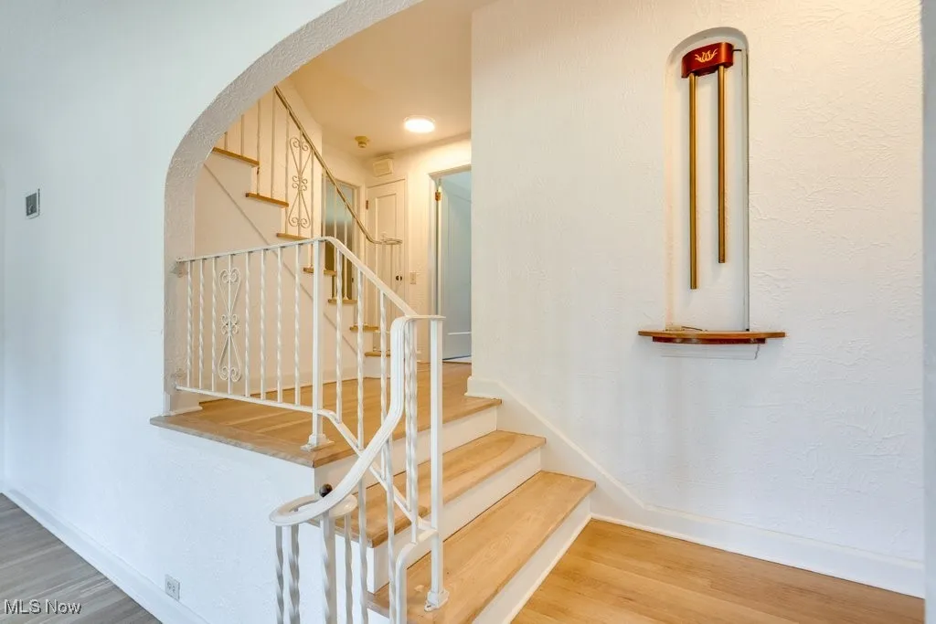 Stairs featuring arched walkways and wood finished floors