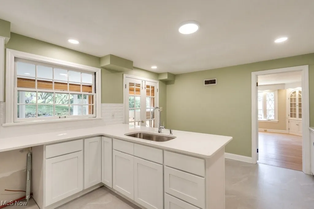 Kitchen featuring recessed lighting, a peninsula, light countertops, and white cabinetry