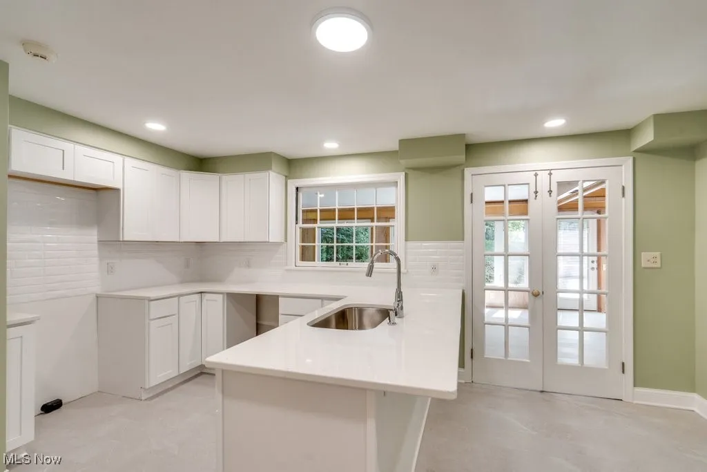 Kitchen featuring french doors, backsplash, white cabinets, and recessed lighting