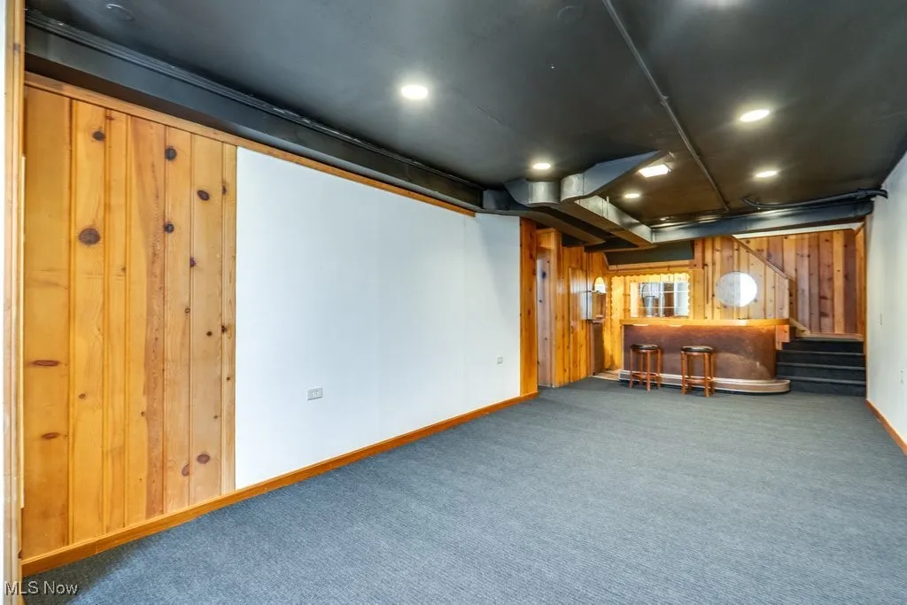 Cinema room with carpet floors, wooden walls, recessed lighting, and bar