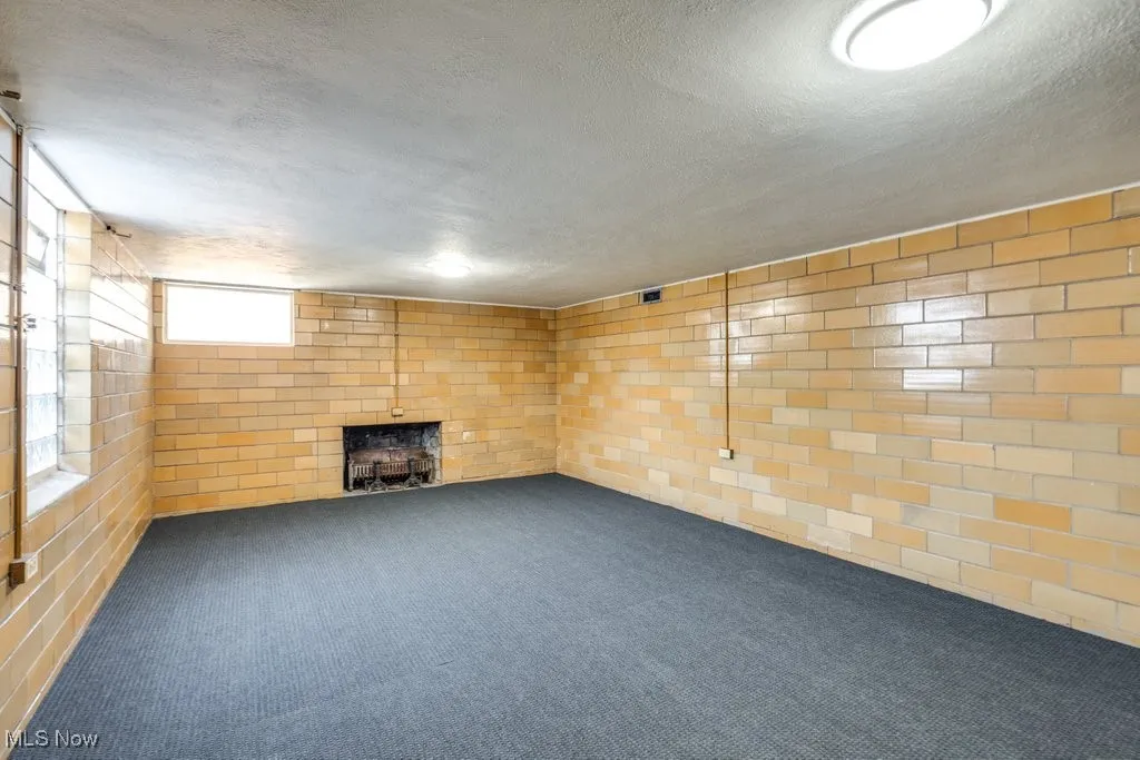 Basement with a brick fireplace, a textured ceiling, and carpet floors