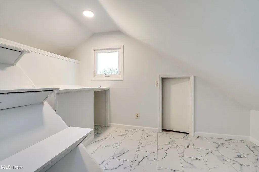Bonus room with lofted ceiling, light marble finish floors, and recessed lighting