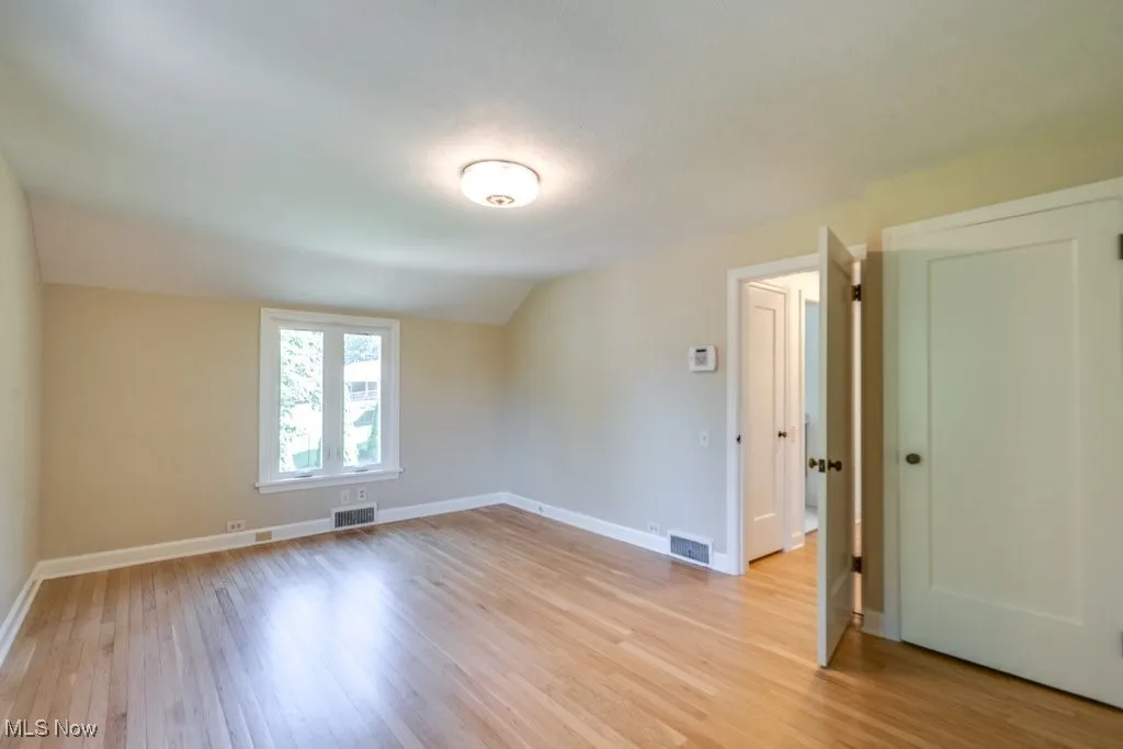Empty room with light wood finished floors and vaulted ceiling