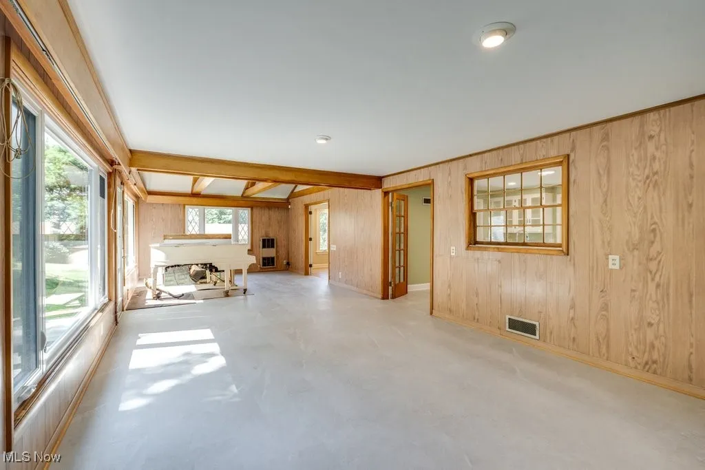 Unfurnished room featuring wood walls, healthy amount of natural light, and concrete floors