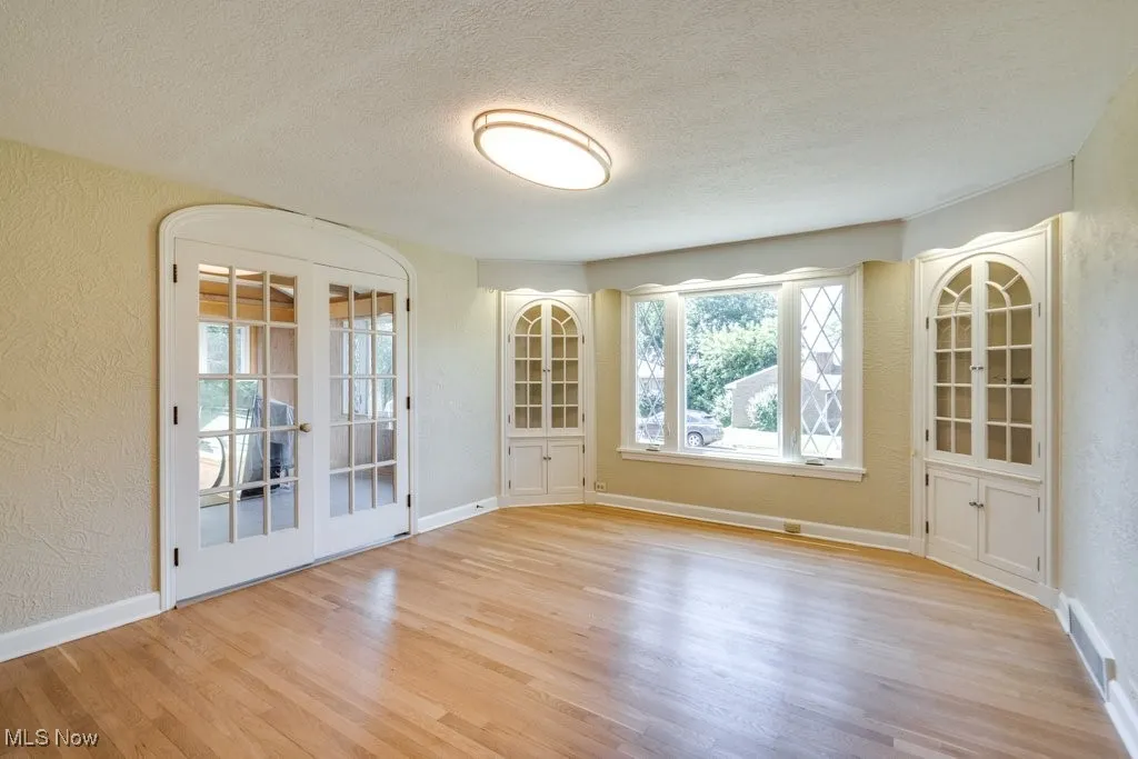 Spare room with a textured wall, wood finished floors, and a textured ceiling