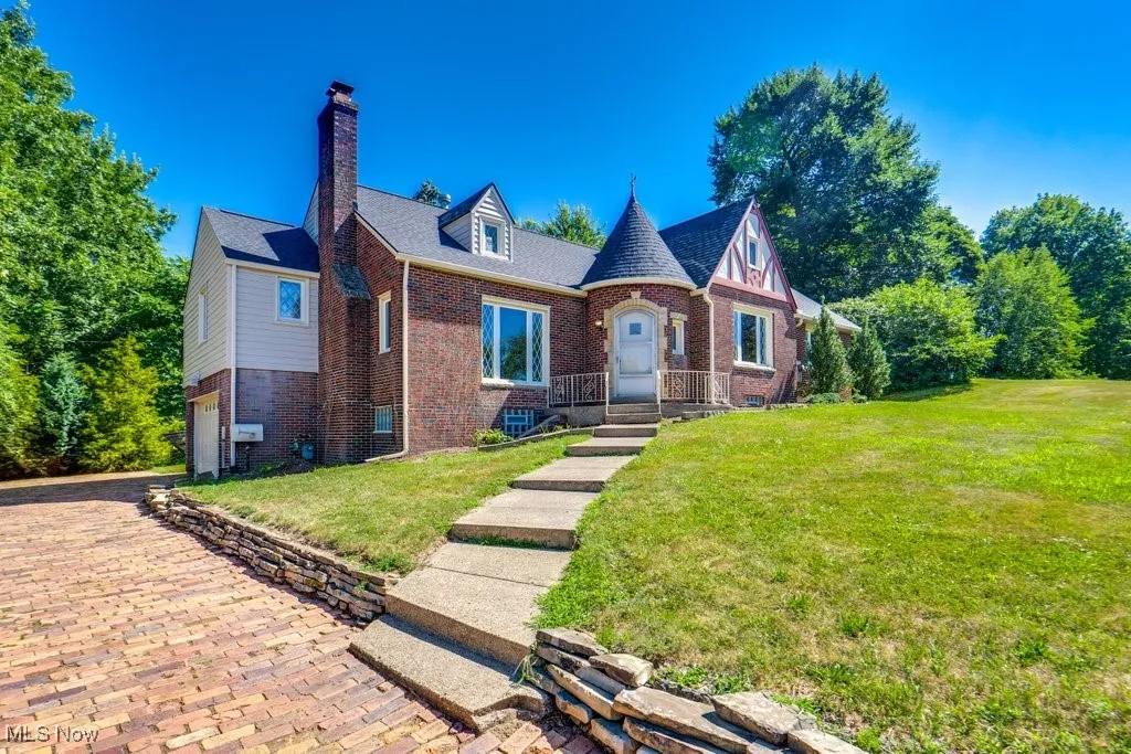 English style home featuring brick siding, a chimney, a front yard, and a shingled roof