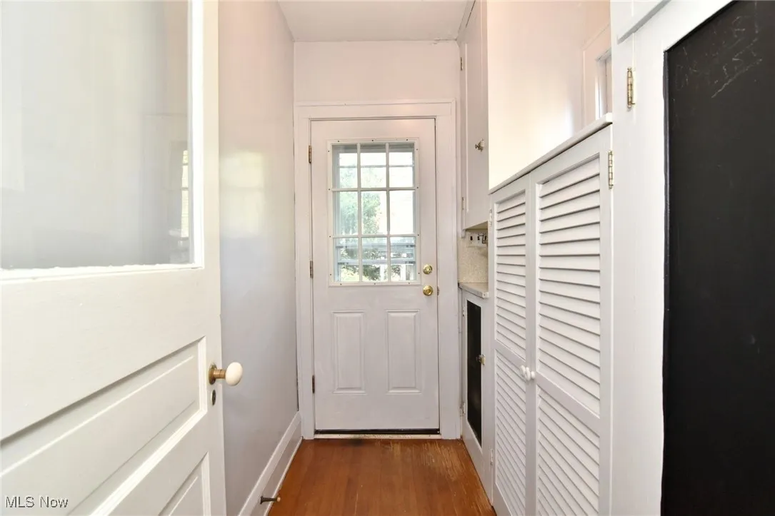 Doorway to outside featuring dark wood-type flooring and baseboards