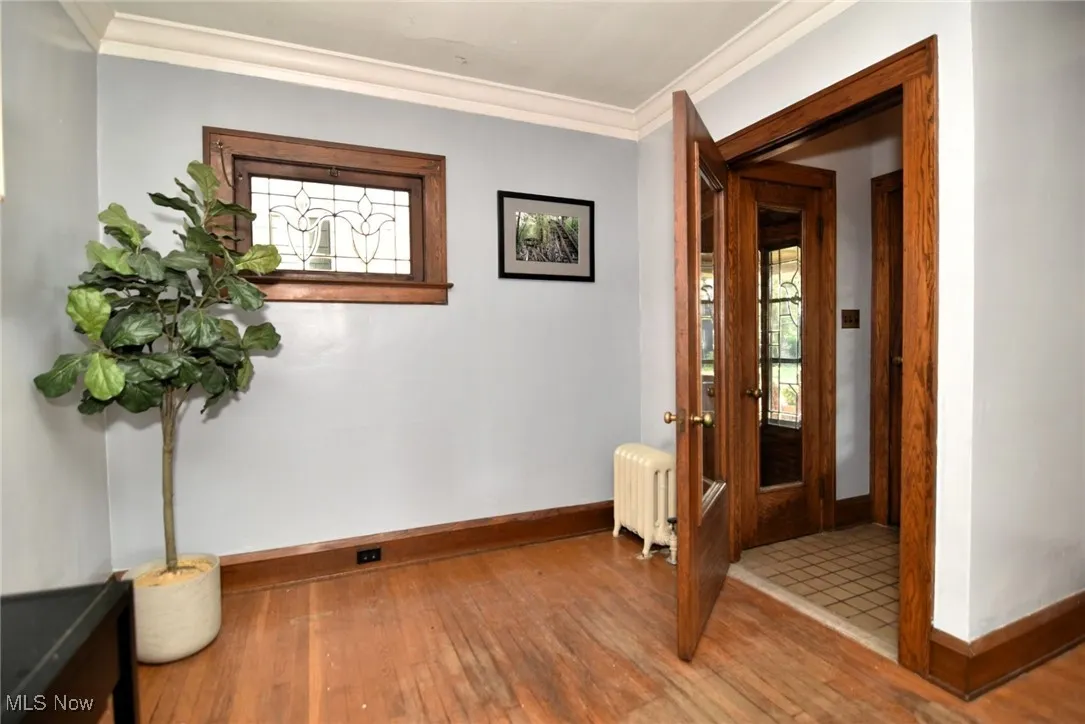 Corridor featuring hardwood / wood-style flooring, radiator, and crown molding