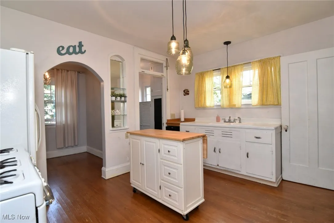 Kitchen featuring stove, white cabinetry, dark wood-type flooring, and freestanding refrigerator