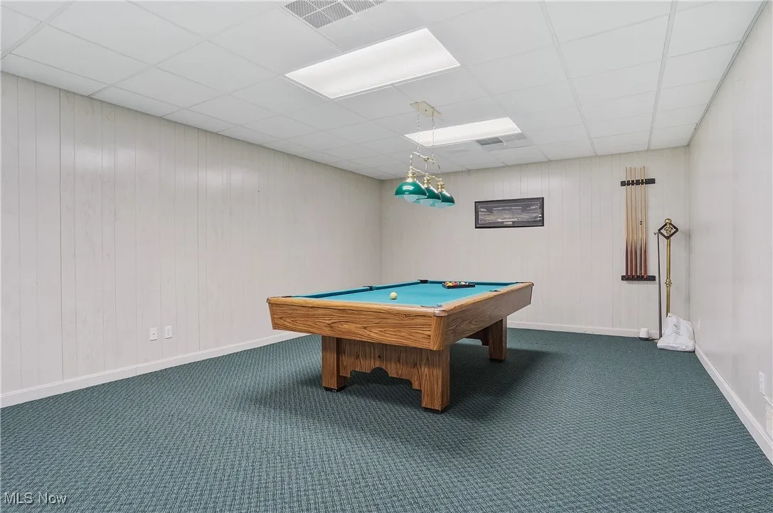 Playroom featuring dark carpet, pool table, wooden walls, and a paneled ceiling