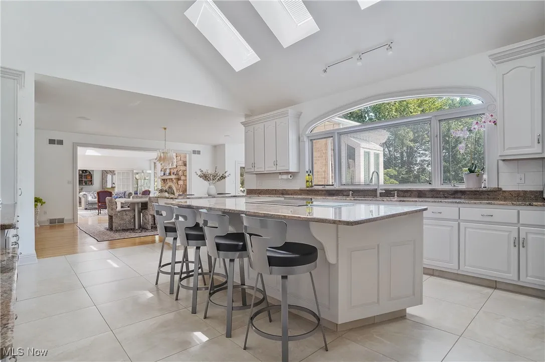Kitchen featuring light tile patterned floors, light stone countertops, plenty of natural light, and high vaulted ceiling