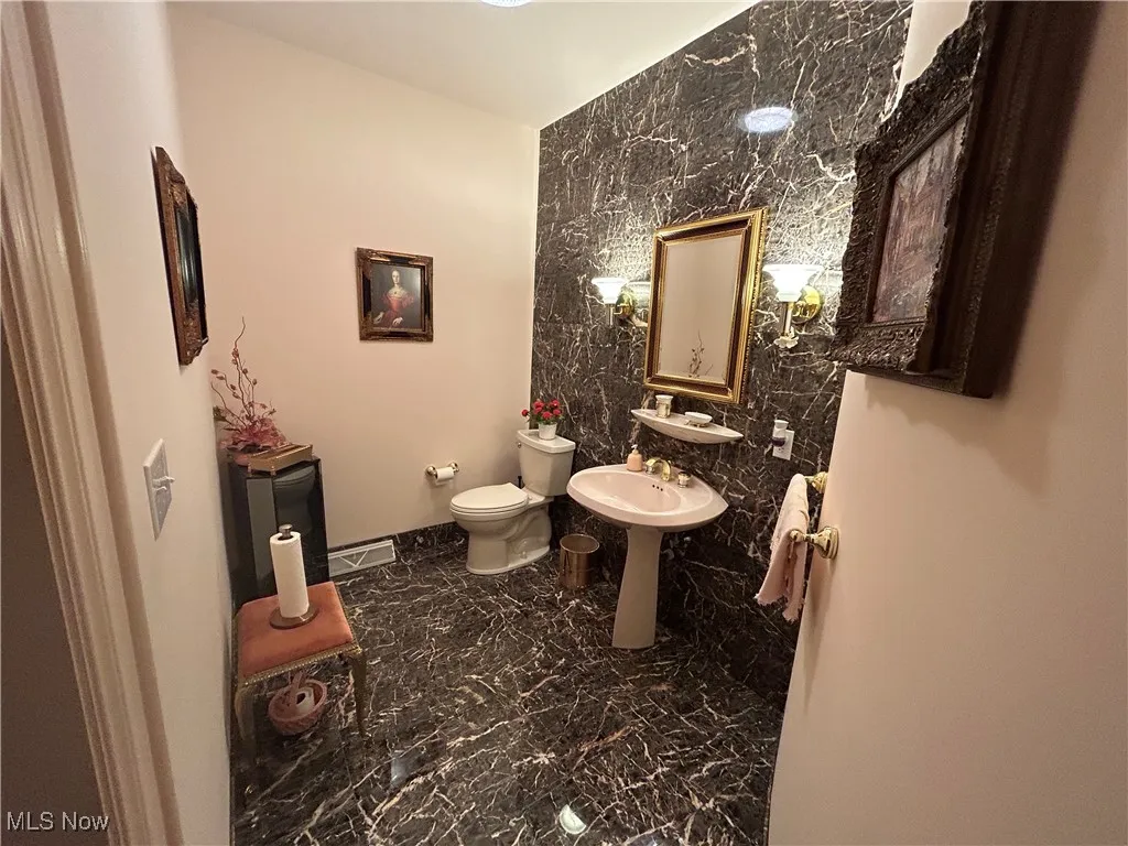 Half bathroom featuring marble finish flooring and tile walls