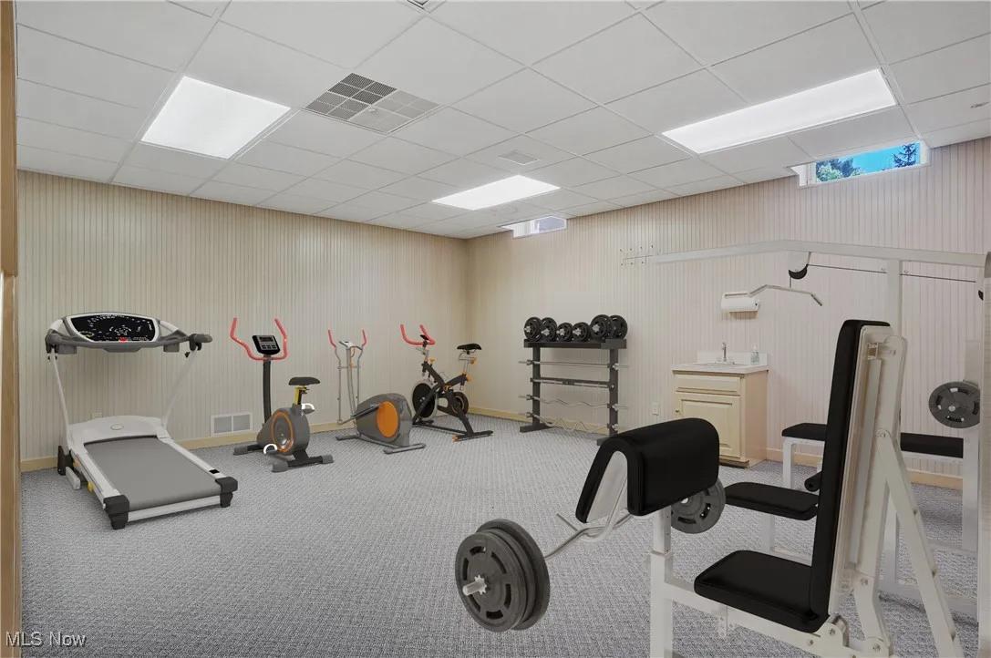 Exercise room with a paneled ceiling and carpet floors