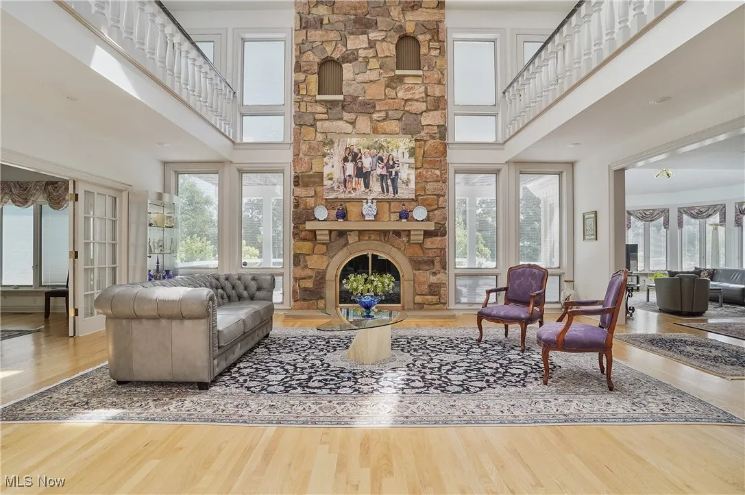 Living area with wood finished floors, healthy amount of natural light, a towering ceiling, and a fireplace