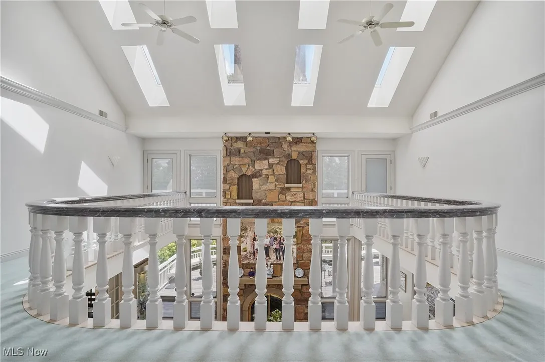 Hall featuring a skylight, high vaulted ceiling, and plenty of natural light