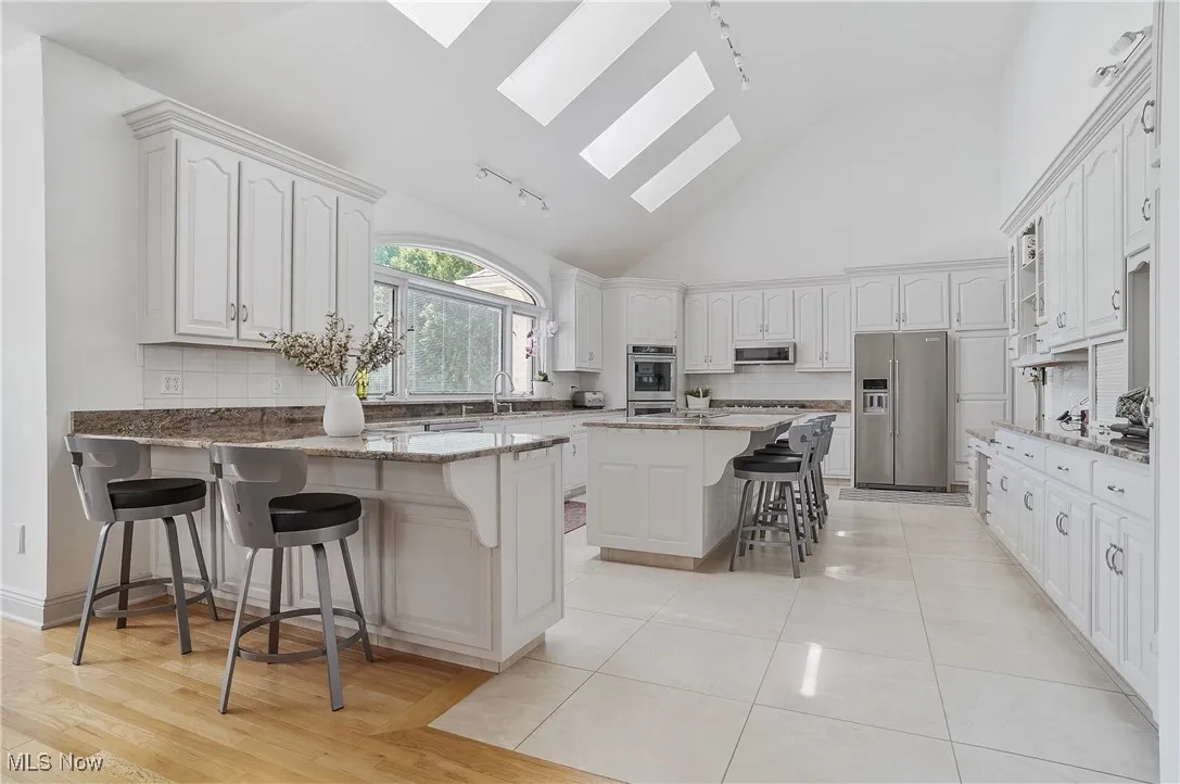 Kitchen featuring a skylight, rail lighting, tasteful backsplash, a peninsula, and a breakfast bar
