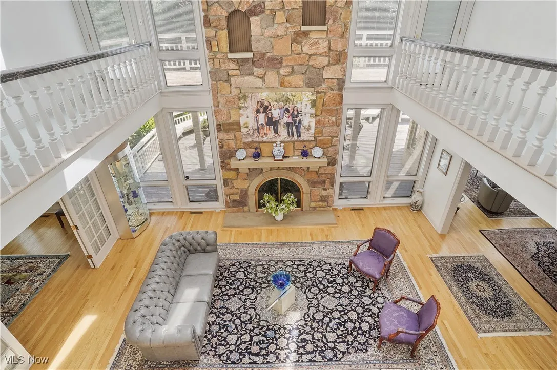Living area with a towering ceiling, a fireplace, wood finished floors, and stairs